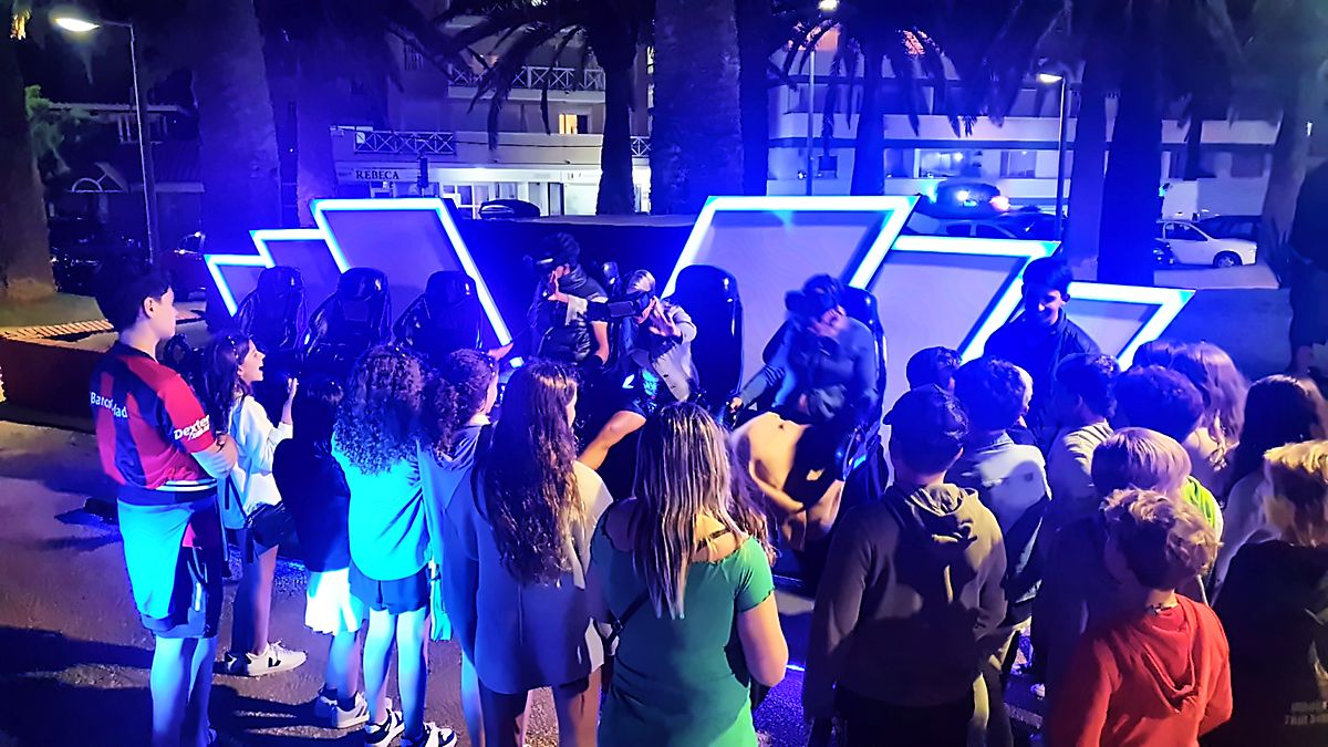 Público reunido alrededor del cine VR Experience en la plaza, de noche